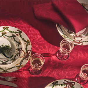 Elegant borddekk med røde stoffservietter fra Royal Copenhagen, kombinert med porselen og juledekorasjoner, perfekt for julemiddager.