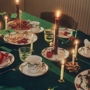 Julemiddag med stearinlys i rød og grønn farge på et pent dekket bord, skaper en koselig atmosfære til førjulstiden.