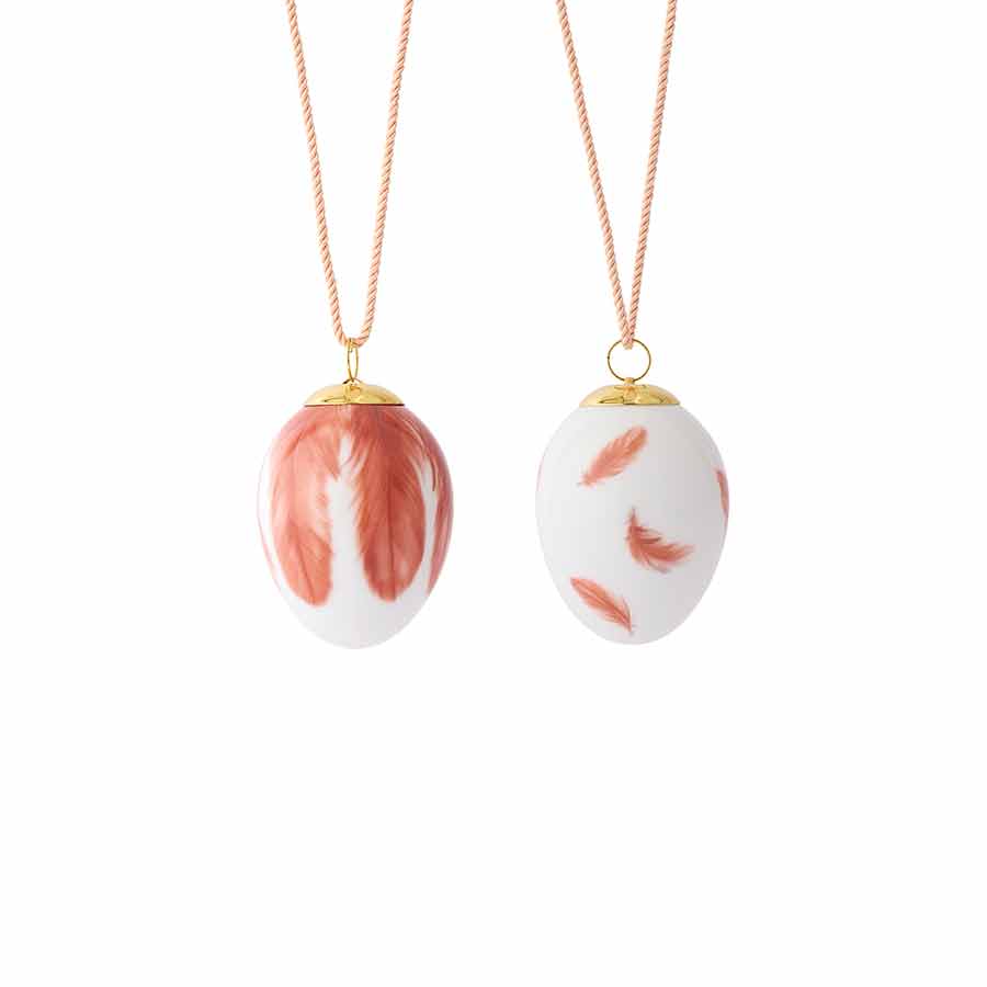 To dekorative egg fra Royal Copenhagen med rødt og oransje fjærmotiv, perfekt til påskepynt eller vårdekorasjon.