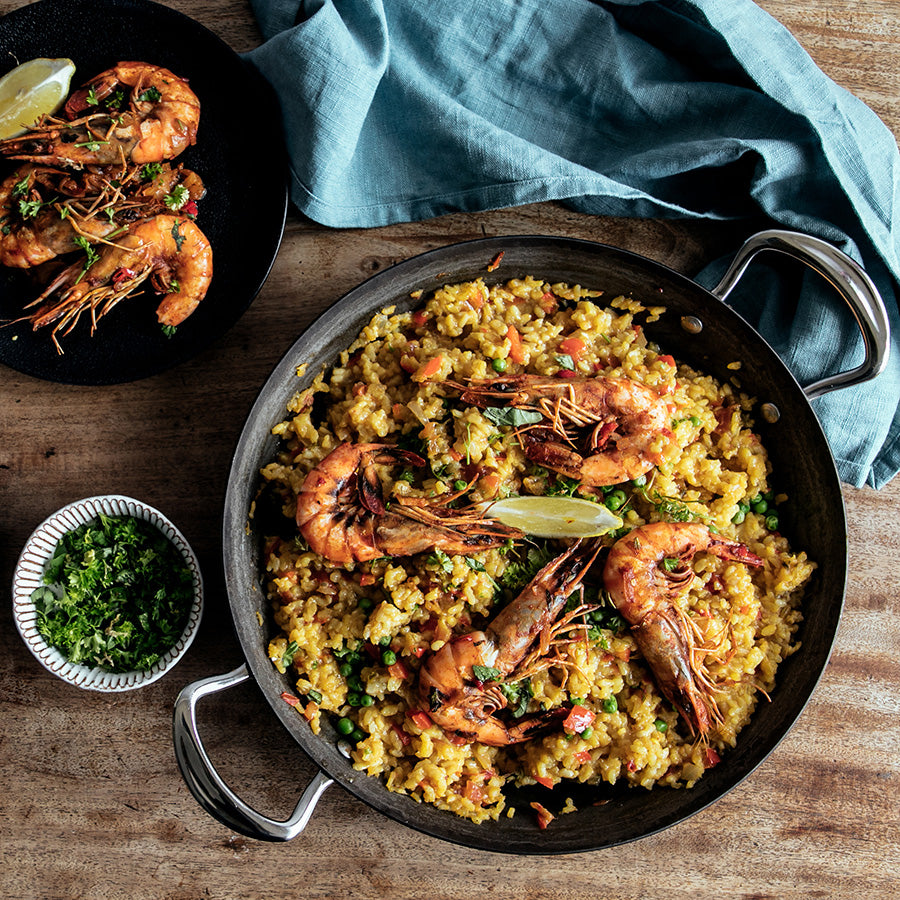Samuel Groves Sautépanne Karbonstål 30cm fylt med risrett og reker, serveres med friske urter og sitron.