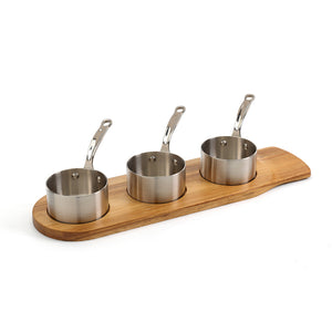 Elegant serveringssett med tre minikasseroller i rustfritt stål, presentert på et trebrett, perfekt for porsjonsservering av tapas og sauser.
