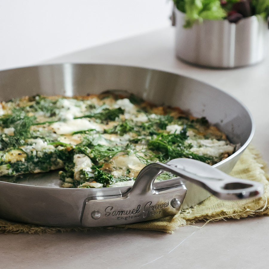 Samuel Groves stekepanne i rustfritt stål i bruk, med grønnsaker og urter, demonstrerer stekepannens evne til å lage deilige retter.