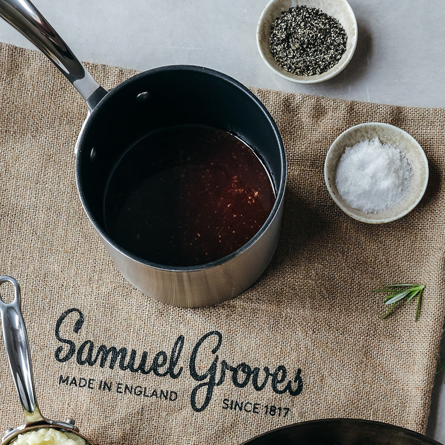 Samuel Groves melkekasserolle med fokus på innholdet, plassert på en tekstil underlag med krydder rundt.