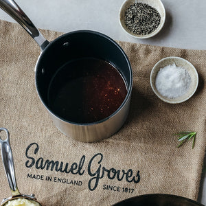 Samuel Groves melkekasserolle med fokus på innholdet, plassert på en tekstil underlag med krydder rundt.