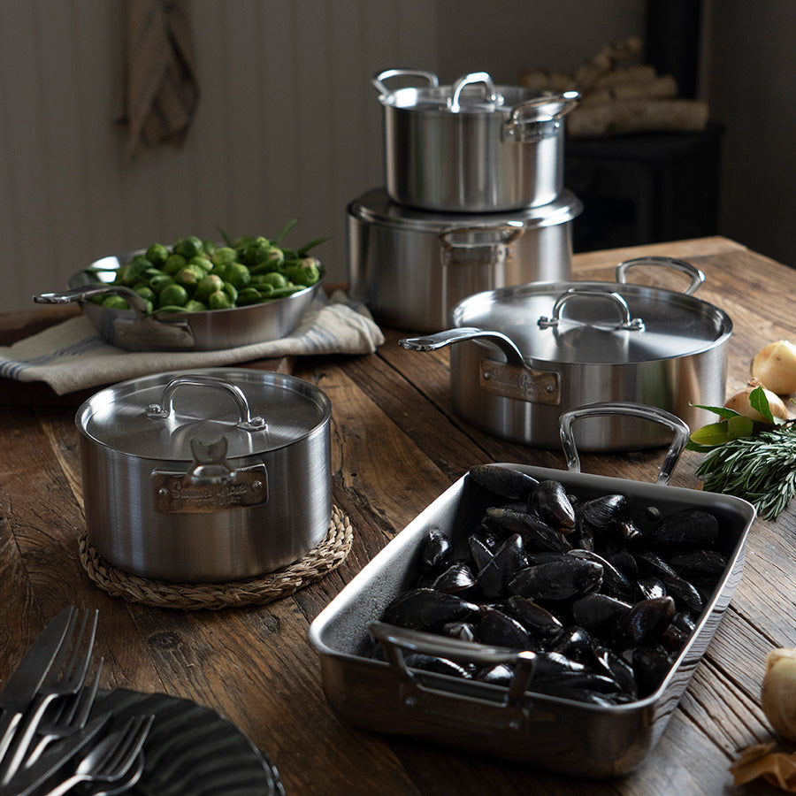 Samlet bilde av Samuel Groves gryter i rustfritt stål på bord, inkludert gryte med lokk, ideell for ulike retter.