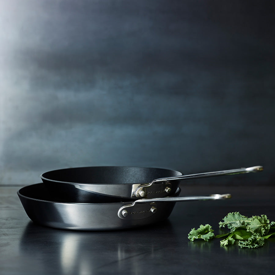 Scanpan stekepannesett bestående av to panne i moderne design, med non-stick overflate, plassert på en mørk bakgrunn.