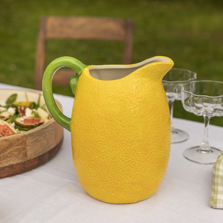 Nærbilde av sitronformet Mugge fra Seasons Capri Collection, med grønn helletut, omgivelsene med grønne hager og sommerstemning.