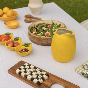 Mugge fra Seasons Capri Collection i sitronform, fylt med iskald drikke, plassert på et sommerbord med friske salater og frukt.