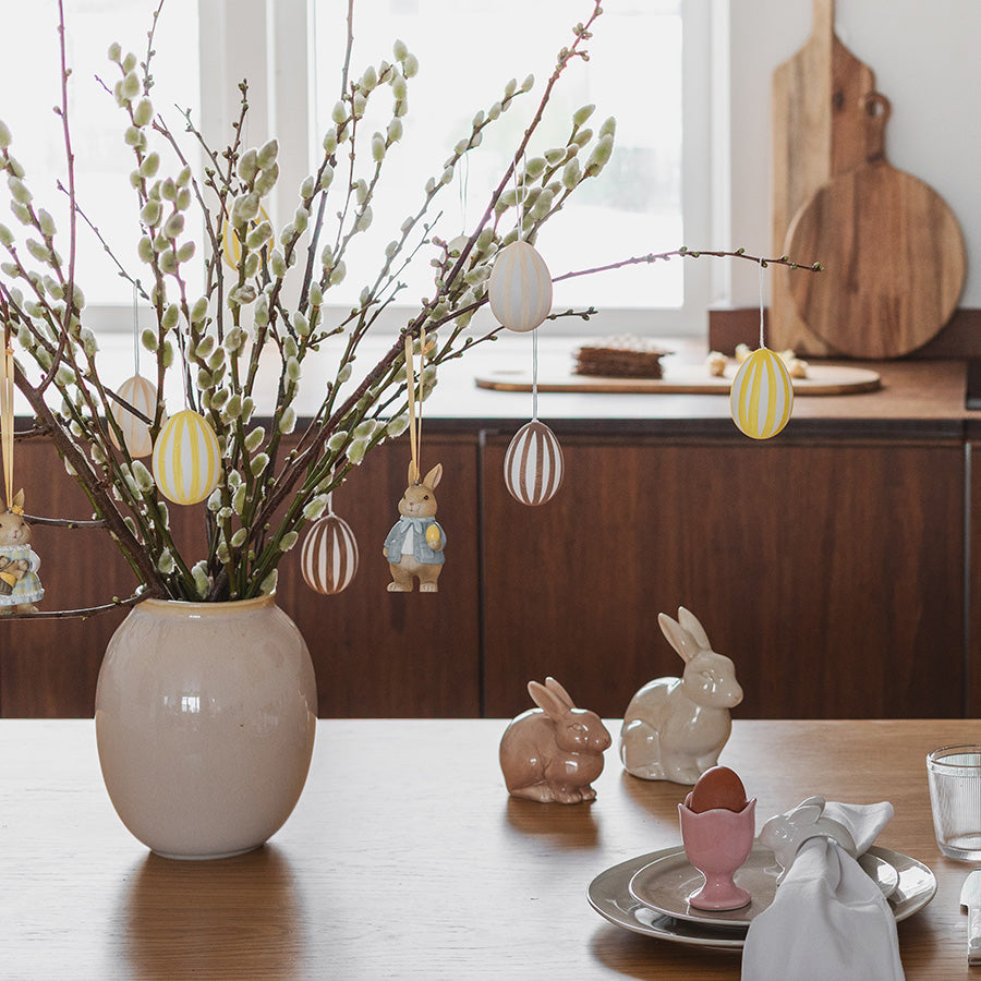 Vase med gåsungekvister og hengepynt fra Seasons, inkludert harefar og påskeegg, skaper en koselig påskestemning.