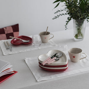 Seasons Love Collection krus med rødt hjerte, sammen med hjerteformede tallerkener og skjeer på et elegant dekket bord.