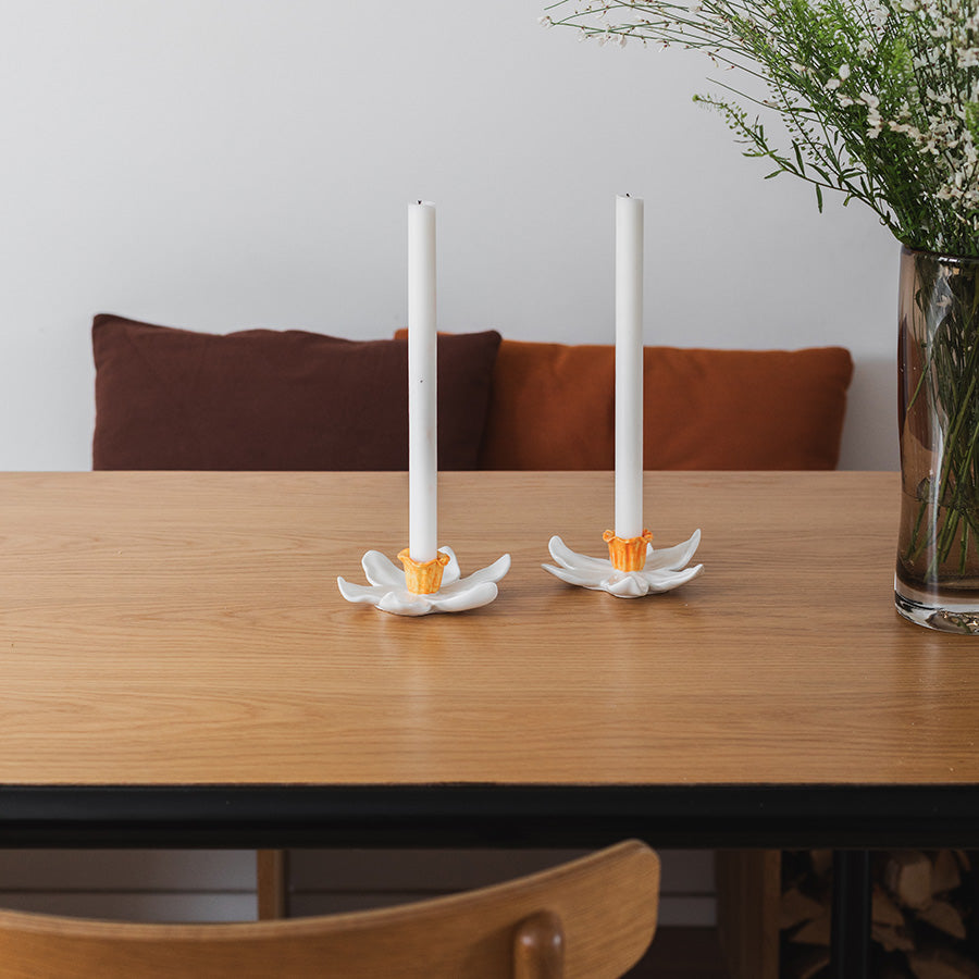 Seasons Lysestake Blomst 2pk Hvit – To lysestaker plassert på et spisebord, med hvite blomsterdesign og telys, skaper en varm atmosfære i interiøret.