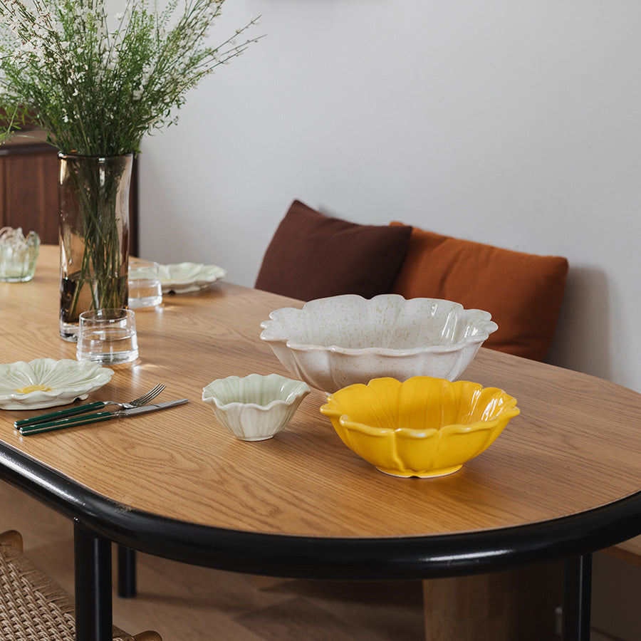 Moderne bordoppsett med flere serveringsskåler i forskjellige størrelser, inkludert en gul blomsterformet serveringsskål.