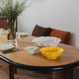 Moderne bordoppsett med flere serveringsskåler i forskjellige størrelser, inkludert en gul blomsterformet serveringsskål.