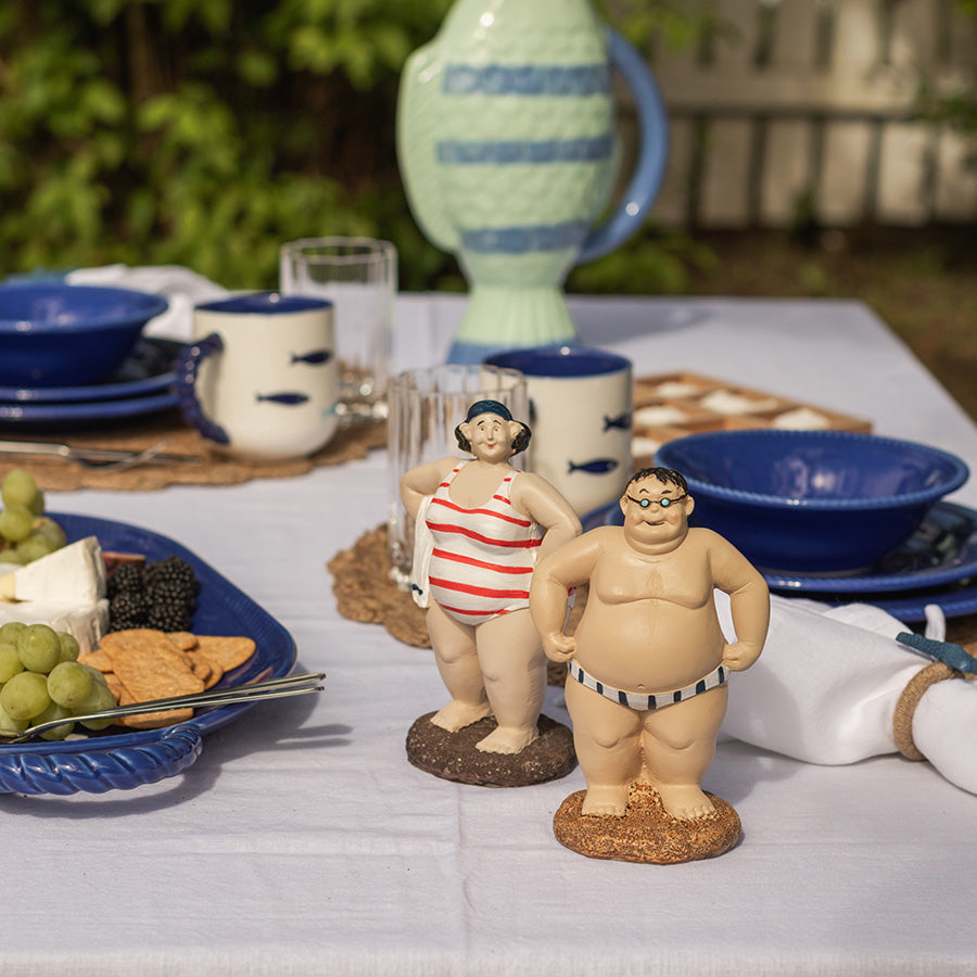 To sjarmerende Bademann figurer i strandantrekk på et bord dekket for sommerlunsj. Ideal for dekorasjon og som gaveidé.