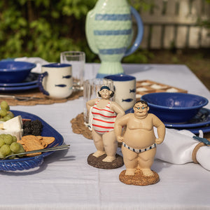 To sjarmerende Bademann figurer i strandantrekk på et bord dekket for sommerlunsj. Ideal for dekorasjon og som gaveidé.