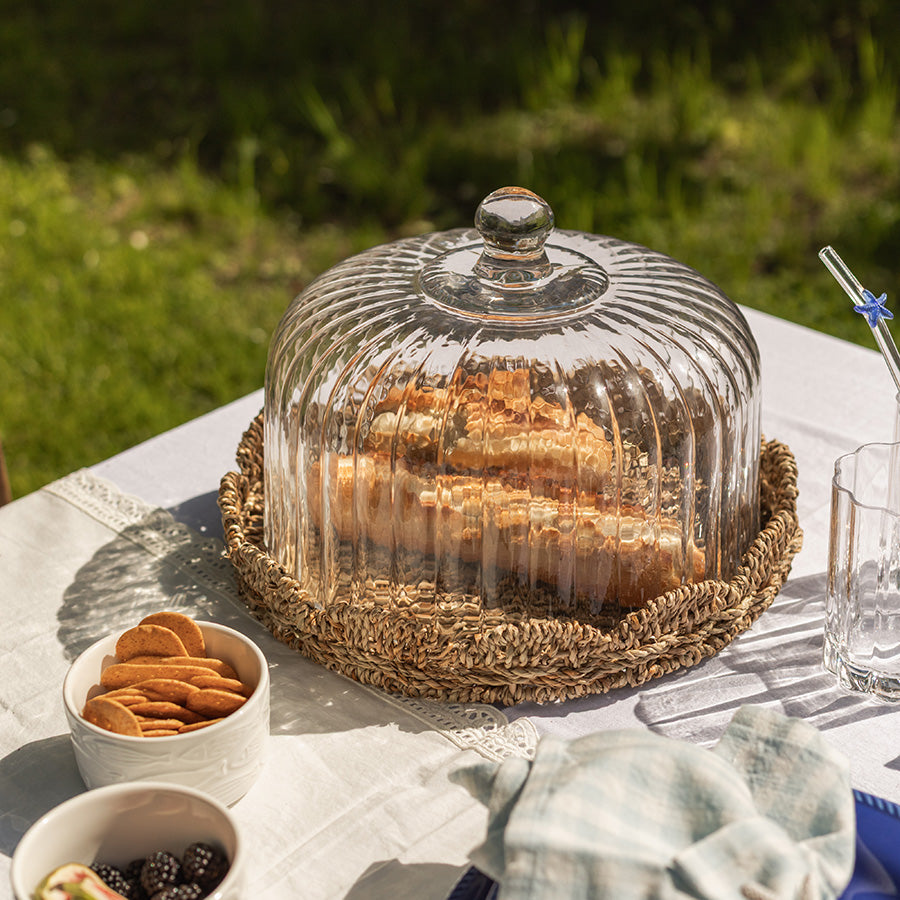 Fat med glasslokk fra Seasons Summer Collection, fylt med fristende bakverk på et picnic-bord i grønt område.