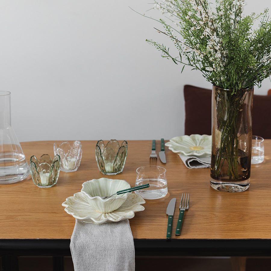 Dekket bord med blomsterformet skål og vakre blomster, som gir et friskt vårpreg til serveringen.