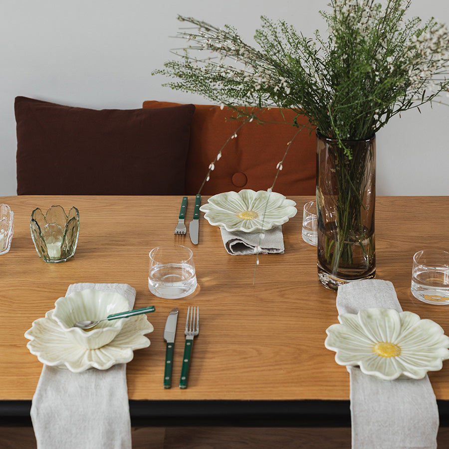 Stilig dekket bord med blomsterformet skål og grønne detaljer som gir en innbydende atmosfære.
