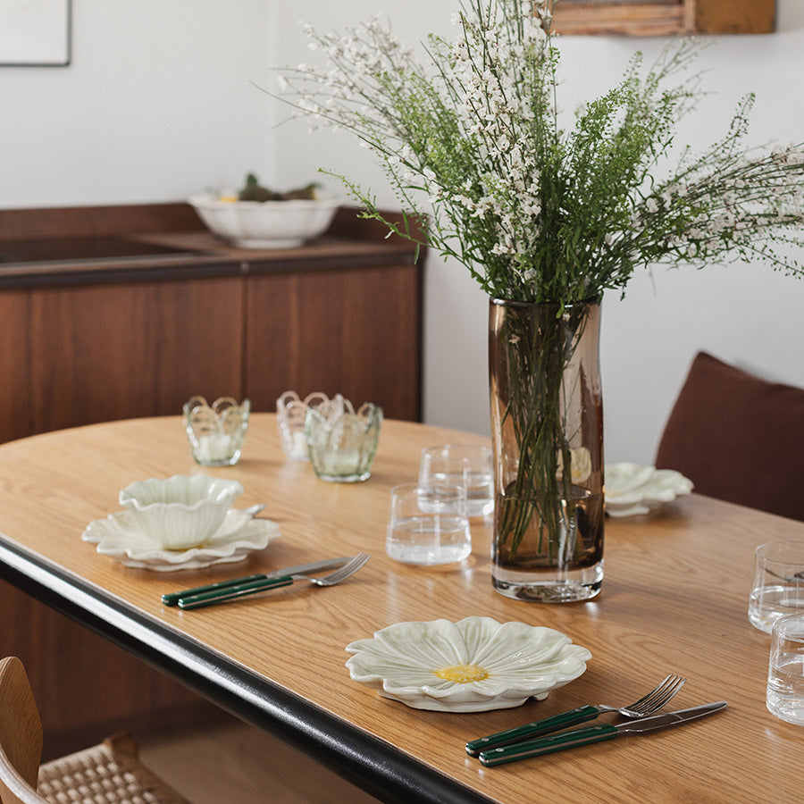 Stilig oppsett med flere blomsterformede tallerkener på et bord, dekorert med blomster.