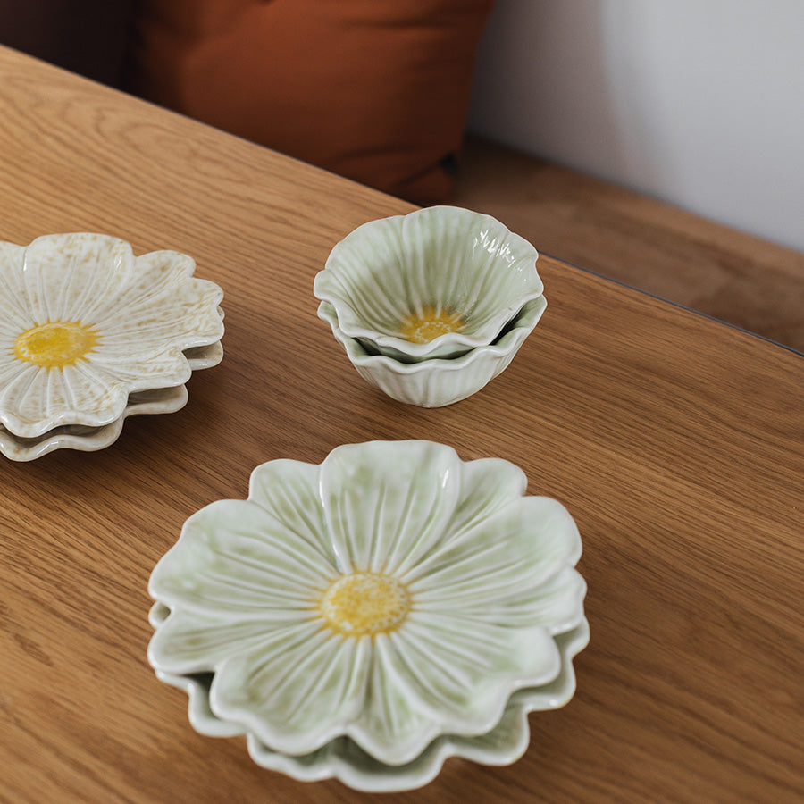 Blomsterformet tallerken i hvit og lys grønn farge, stablet sammen med mindre skåler.
