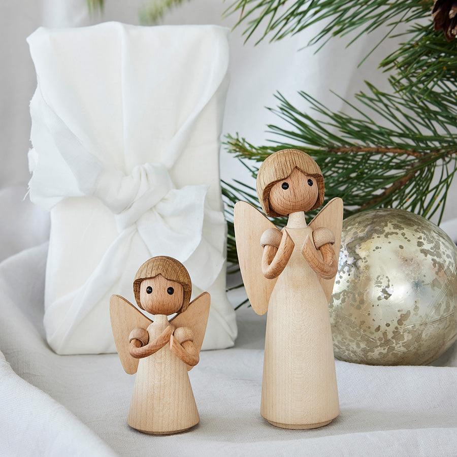 To Spring Copenhagen Aura Trefigur av tre plassert ved en gave, ideell for høytidelig borddekorasjon.