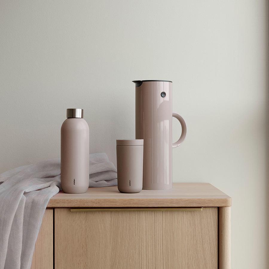 Stelton EM77 termokanne i heather, kombinert med en flaske og et krus, gir et stilrent serveringssett.