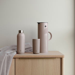 Stelton EM77 termokanne i heather, kombinert med en flaske og et krus, gir et stilrent serveringssett.