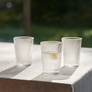 Tre drikkeglass fylt med vann på et bord, godt tilpasset for sommerdager med deres elegante design.