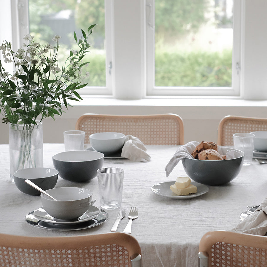 Spisebord dekket med stilige drikkeglass, tallerkener og en vase med blomster, ideelt for hyggelige sammenkomster.
