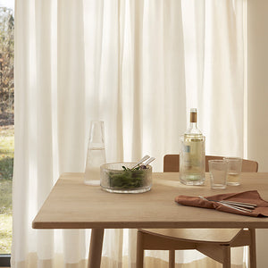 Elegant bordoppsett med Stelton Pilastro serveringsbolle, dekorert med grønn salat og glassvann på et lyst trebord.