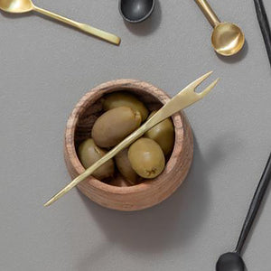 Gylden serveringsgaffel plassert i en trekopp fylte med oliven, som viser den allsidige bruken av serveringsgaffel.