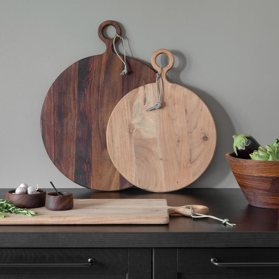 To forskjellige størrelser av trefjøl i akasietre mot en grå vegg, ideelle for servering av mat og stilfull dekorasjon.