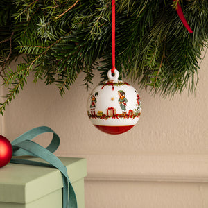 Årets julekule 2026 fra Villeroy & Boch henger på juletregrener med nisser, julegaver og røde detaljer