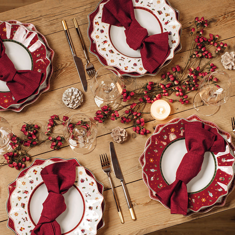 Bord med Villeroy & Boch Toy's Delight tallerkener, pyntet med røde servietter, juleroser og festlig juledekor for et vakkert måltid.