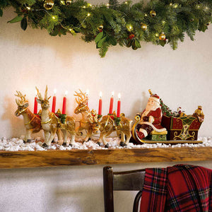 Villeroy & Boch julenisse i slede på peishylla, omgitt av reinsdyr og julepynt med lys.