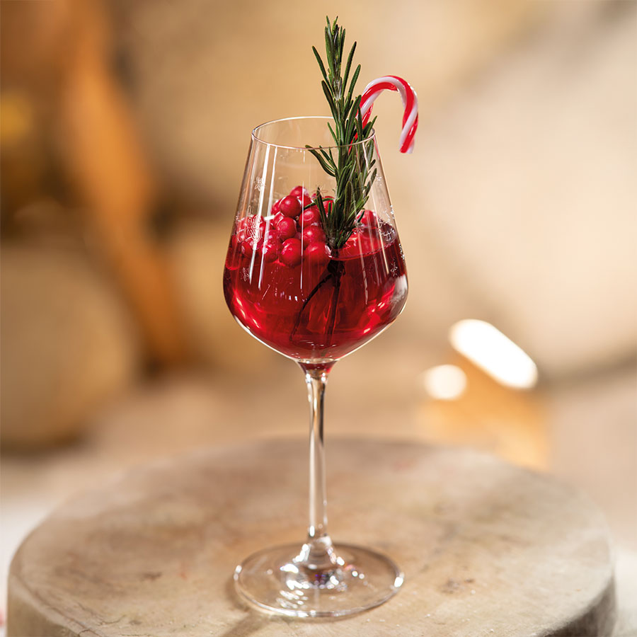Villeroy & Boch hvitvinsglass med en festlig juledrikk, dekorert med grønn rosmarin og godteri.