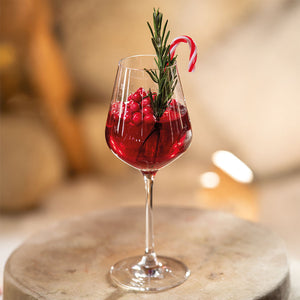 Villeroy & Boch hvitvinsglass med en festlig juledrikk, dekorert med grønn rosmarin og godteri.