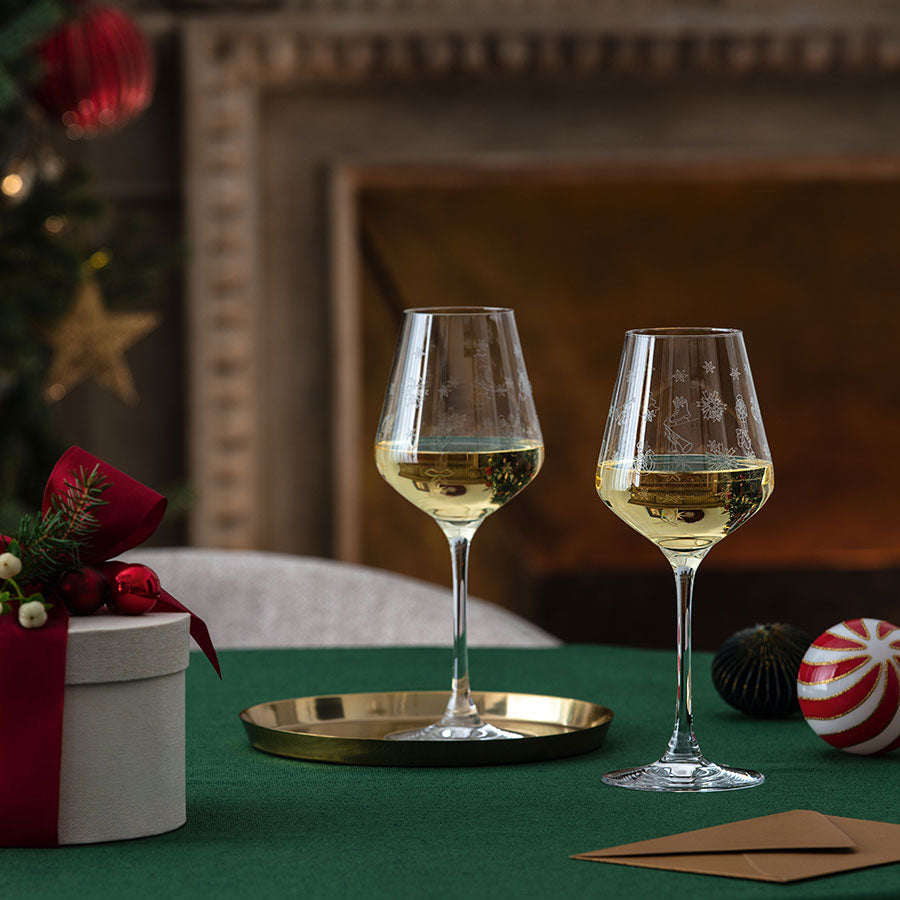 Villeroy & Boch hvitvinsglass på et juledekket bord, ved siden av gaver og juledekorasjoner.