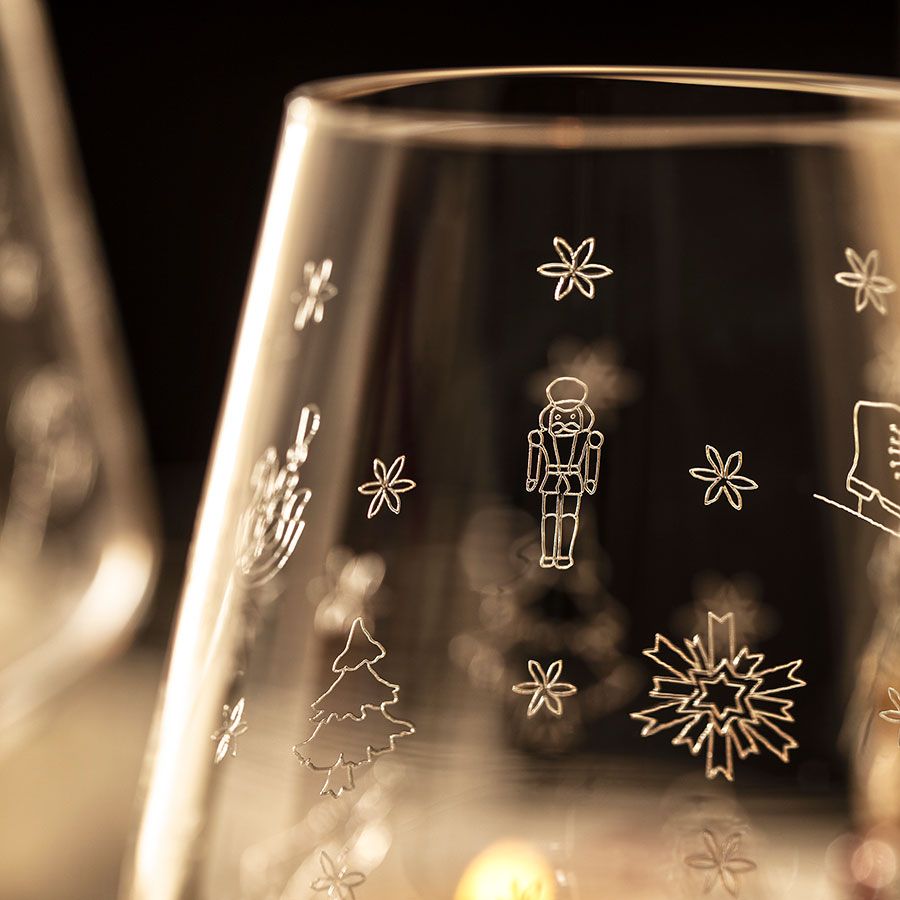 Nærbilde av Villeroy & Boch hvitvinsglass med eleganta juletre graveringer, skaper en nostalgisk atmosfære.