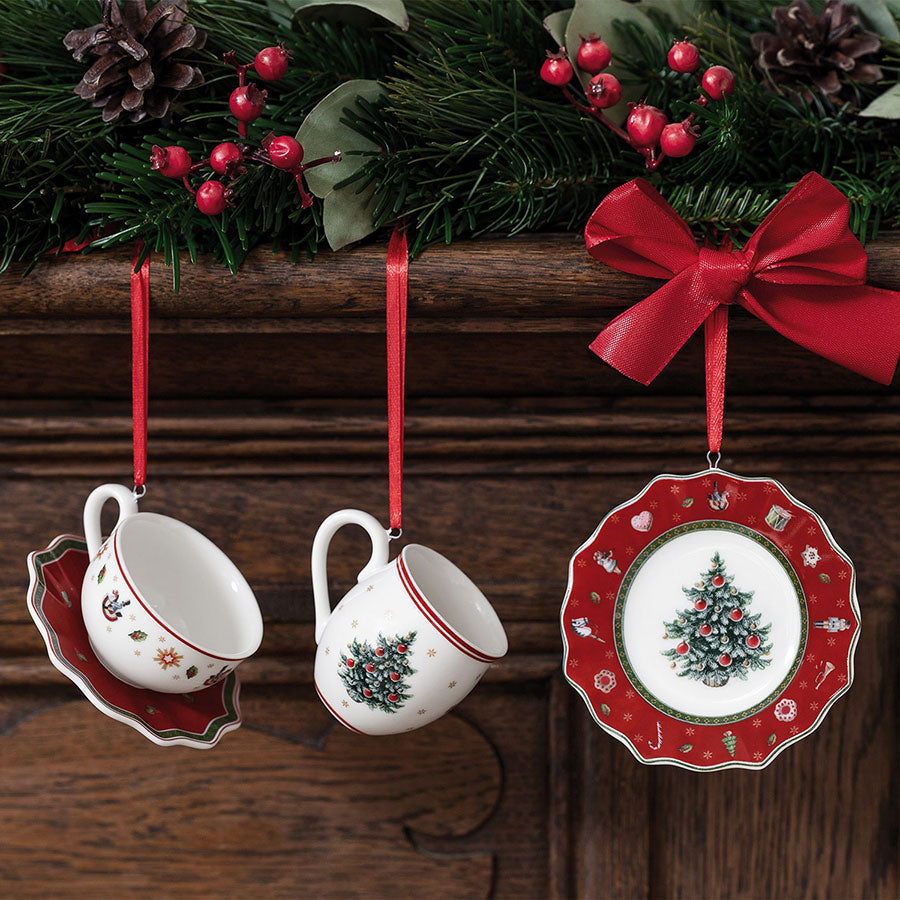 Villeroy & Boch julepynt, dekorasjoner i porselen hengt fra en gren, inkludert to kopper og en miniatyrtallerken med klassiske julemotiver.