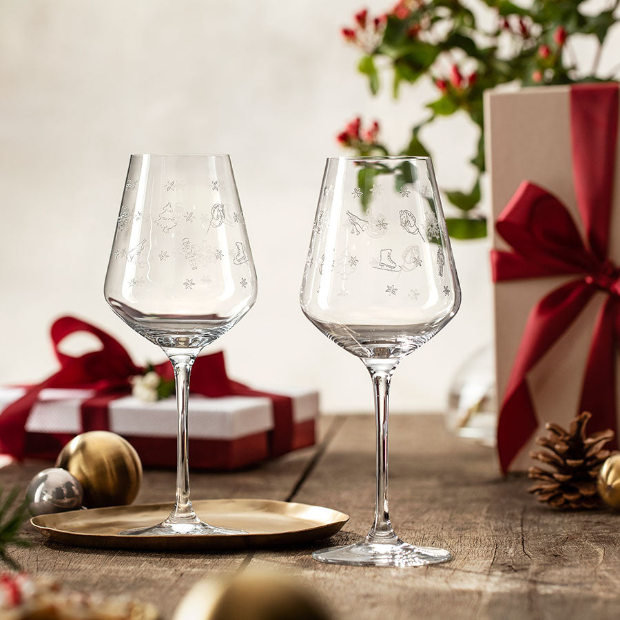 To Villeroy & Boch rødvinsglass med julemotiver på et dekket bord, perfekt for gave eller fest.