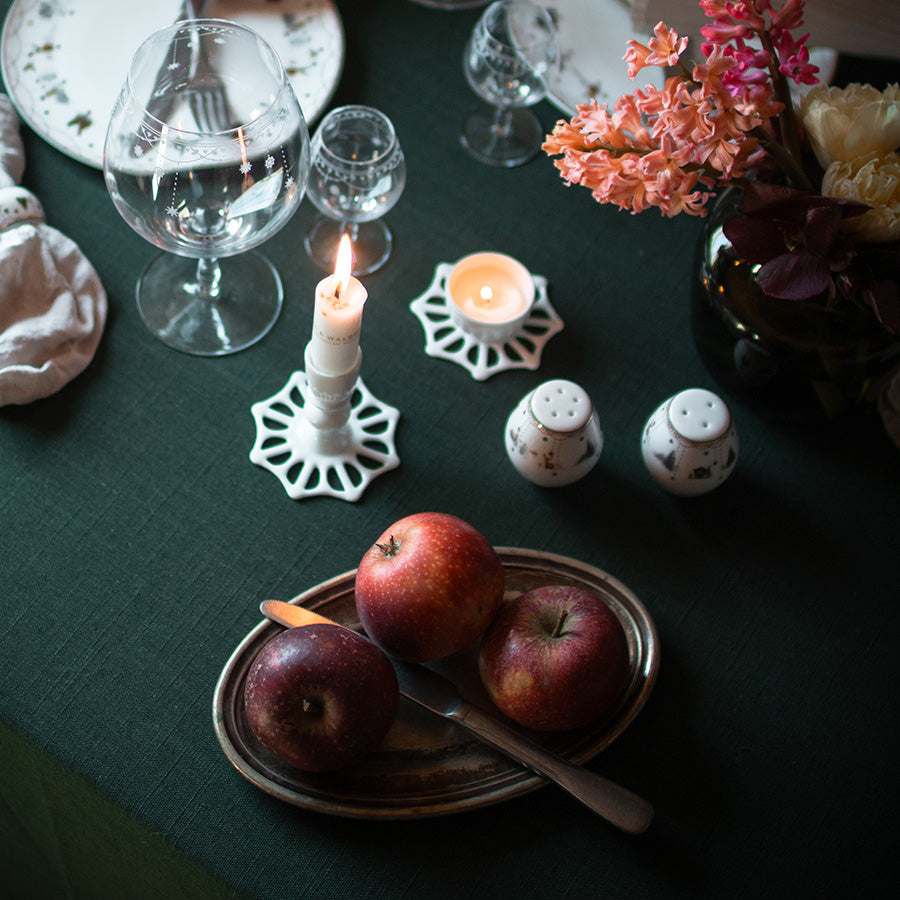 Stemningsfullt julebord med Wik & Walsøe salt- og pepperbøsse, dekket med friske epler, lys og vakre blomster.