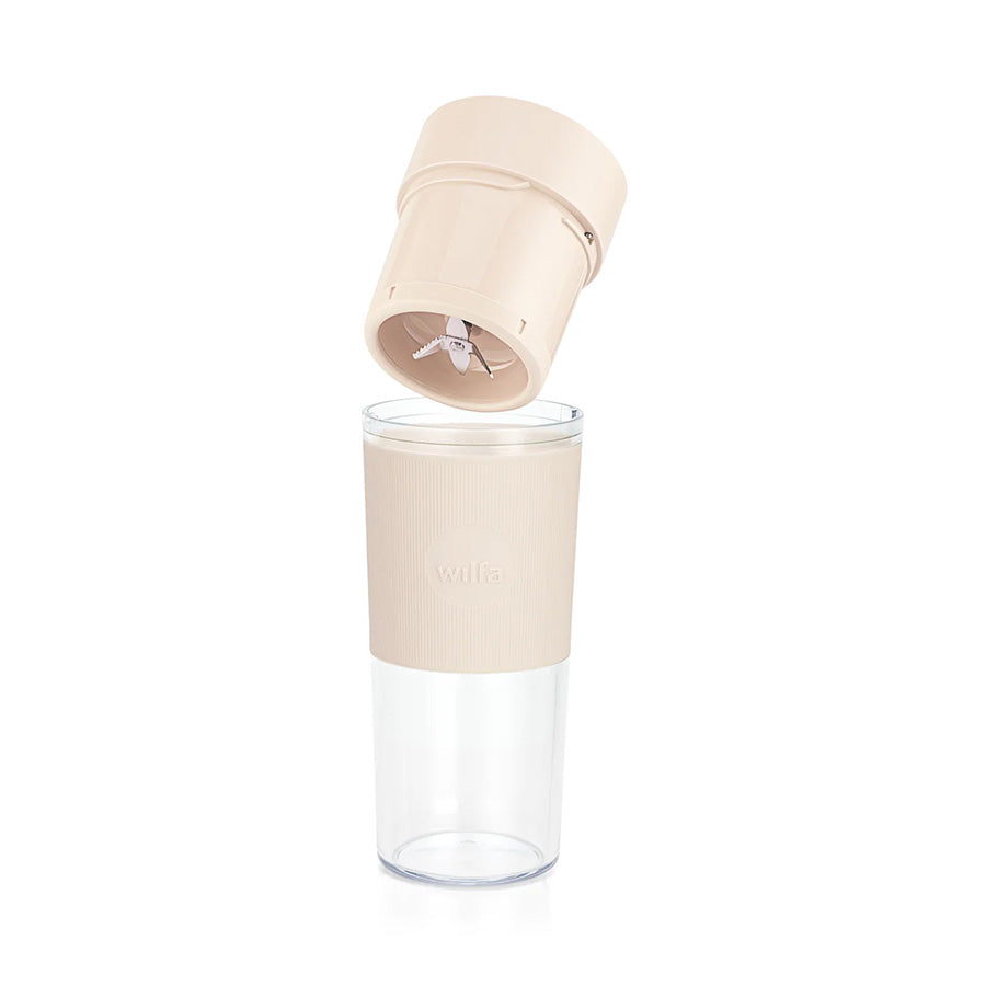 Wilfa bærbar blender i beige, med hevet lokk som viser metalldelene, perfekt for å lage ferske drikker.
